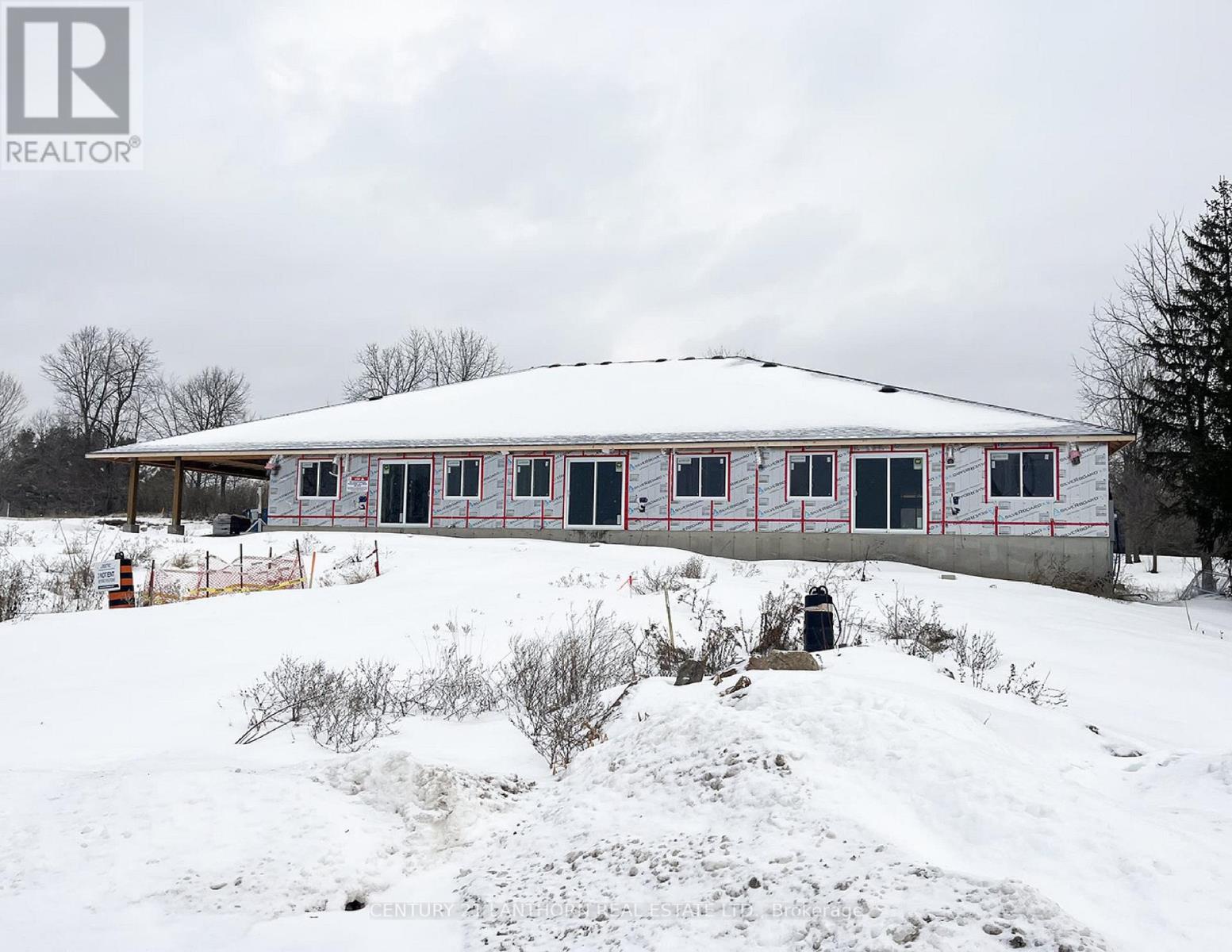 A house with a white roof and red trim is surrounded by snow.