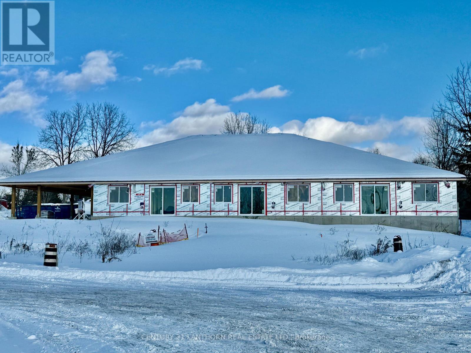 A large white building with a red trim is surrounded by snow.