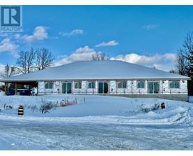 A large white building with a red trim is surrounded by snow.