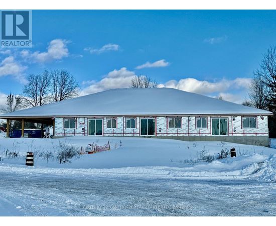 A large white building with a red trim is surrounded by snow.