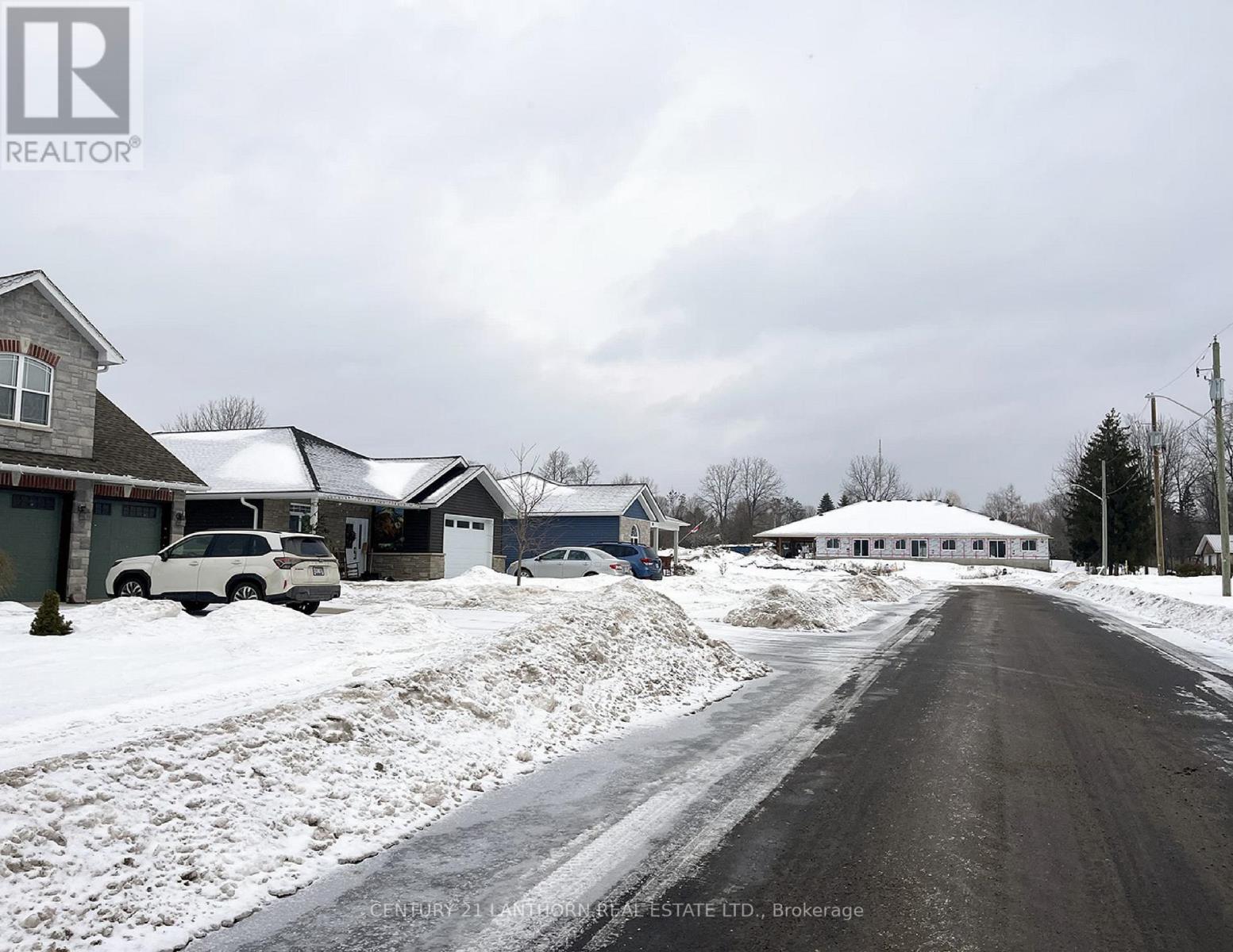 A snowy street with houses on both sides and a car parked on the left.