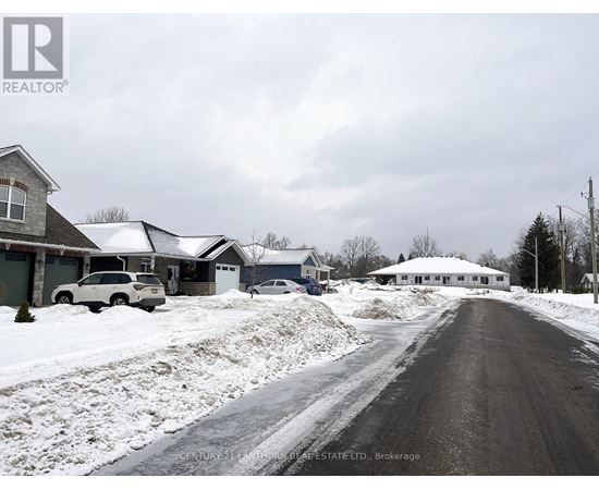 A snowy street with houses on both sides and a car parked on the left.