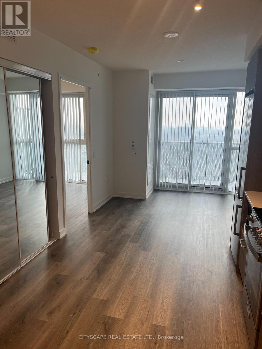 A spacious room with wooden flooring and sliding glass doors.
