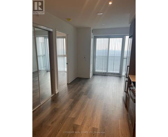 A spacious room with wooden flooring and sliding glass doors.