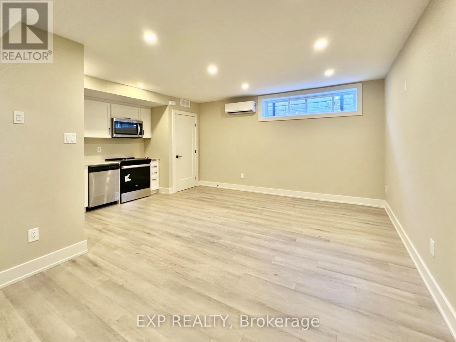 A spacious room with wood flooring and a window.