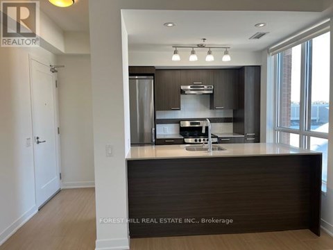 A kitchen with a counter top and a stainless steel refrigerator.