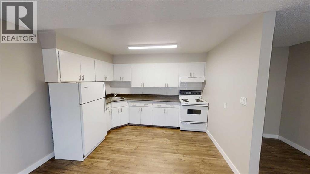 A kitchen with white appliances and cabinets in a room with wooden floors.