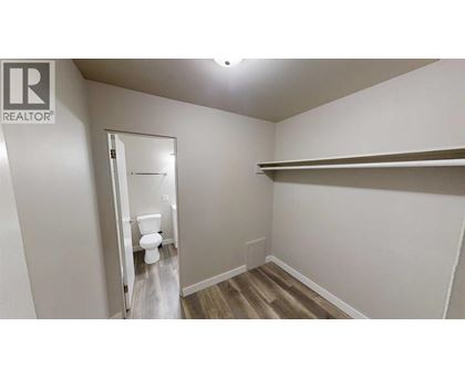 A white bathroom with a toilet and a shelf.