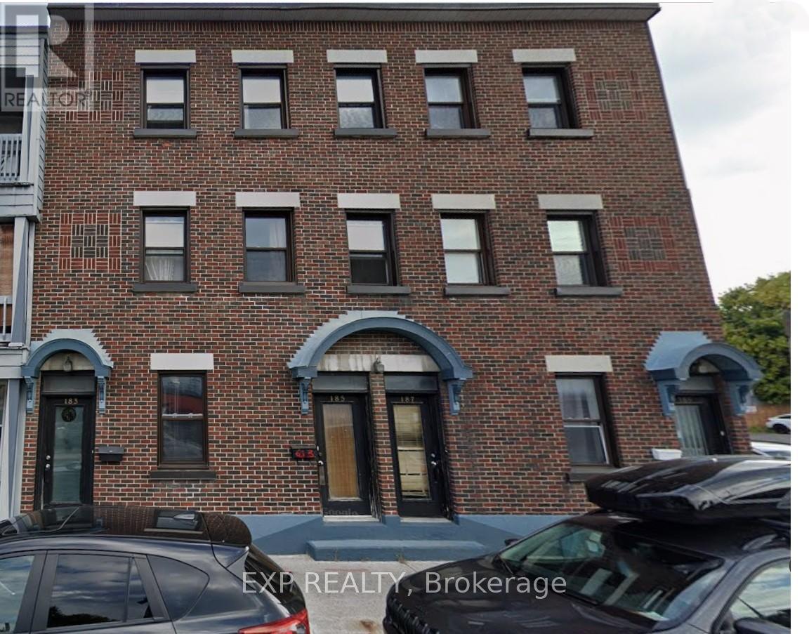 A brick building with a black car in front.