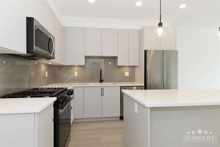 A modern kitchen with white cabinets and a black stove top.