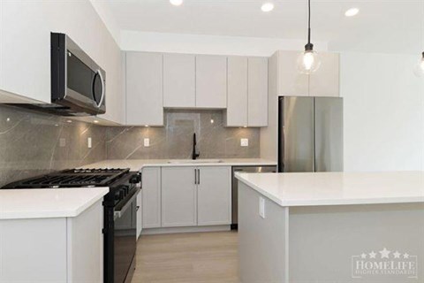 A modern kitchen with white cabinets and a black stove top.