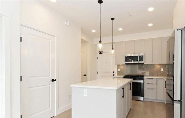 A kitchen with a white island and stainless steel appliances.