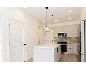 A kitchen with a white island and stainless steel appliances.