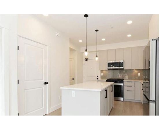 A kitchen with a white island and stainless steel appliances.