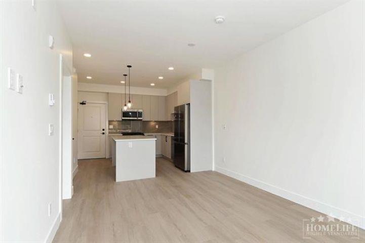 A spacious kitchen with white cabinets and a wooden floor.