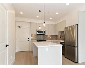 A spacious kitchen with white cabinets and a wooden floor.