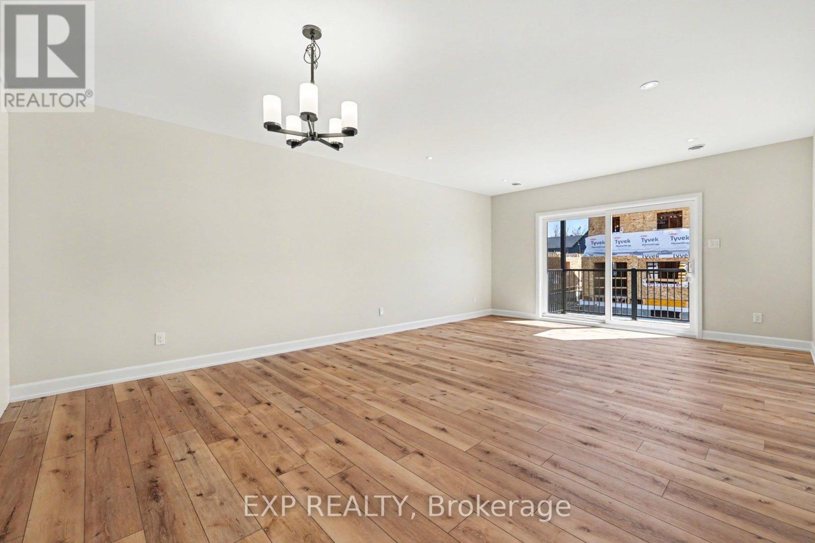 A room with wooden flooring and a chandelier hanging from the ceiling.