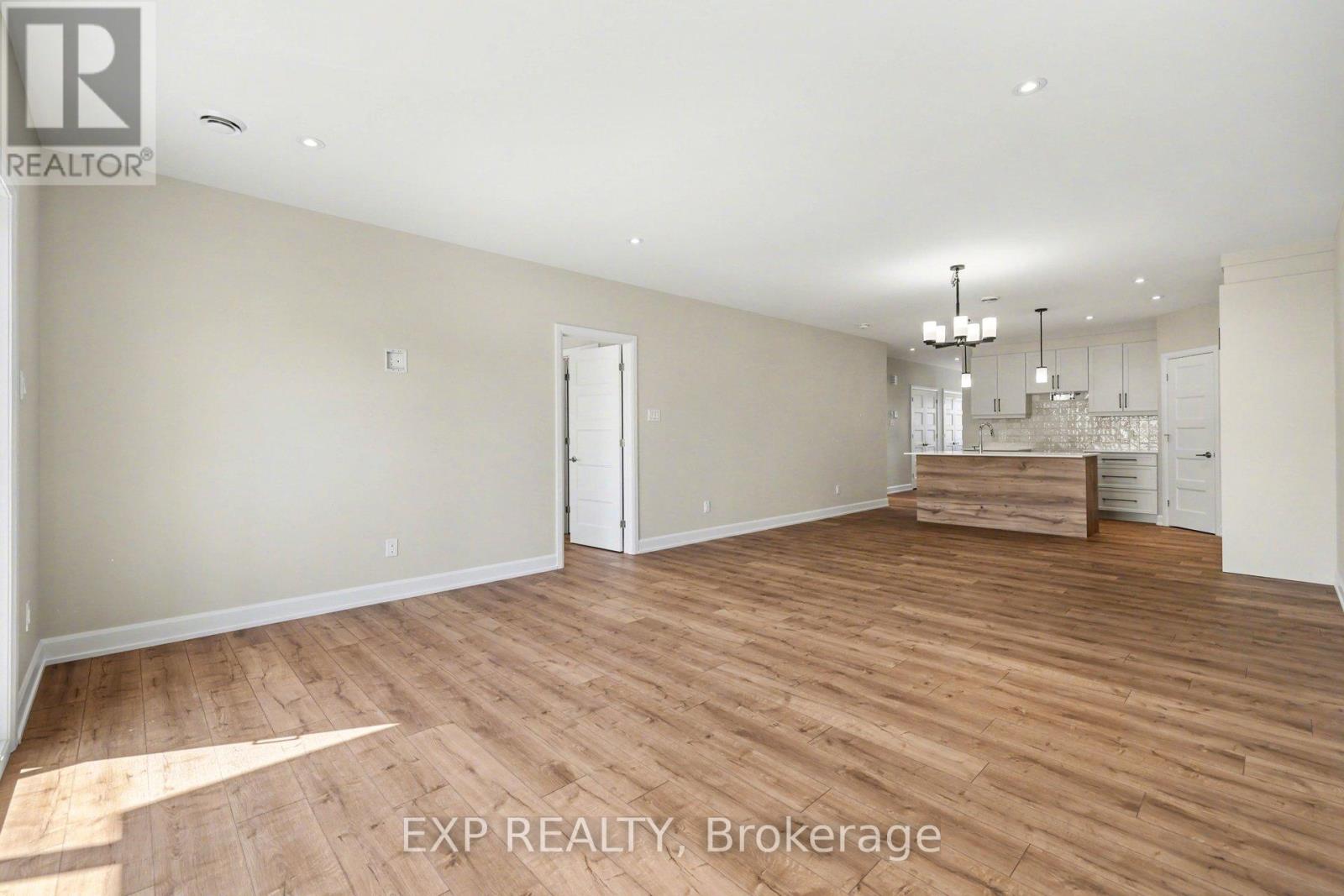 A spacious room with wooden flooring and a chandelier.