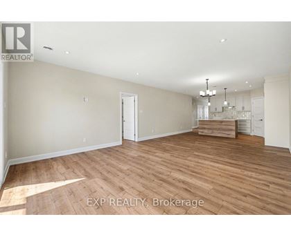 A spacious room with wooden flooring and a chandelier.