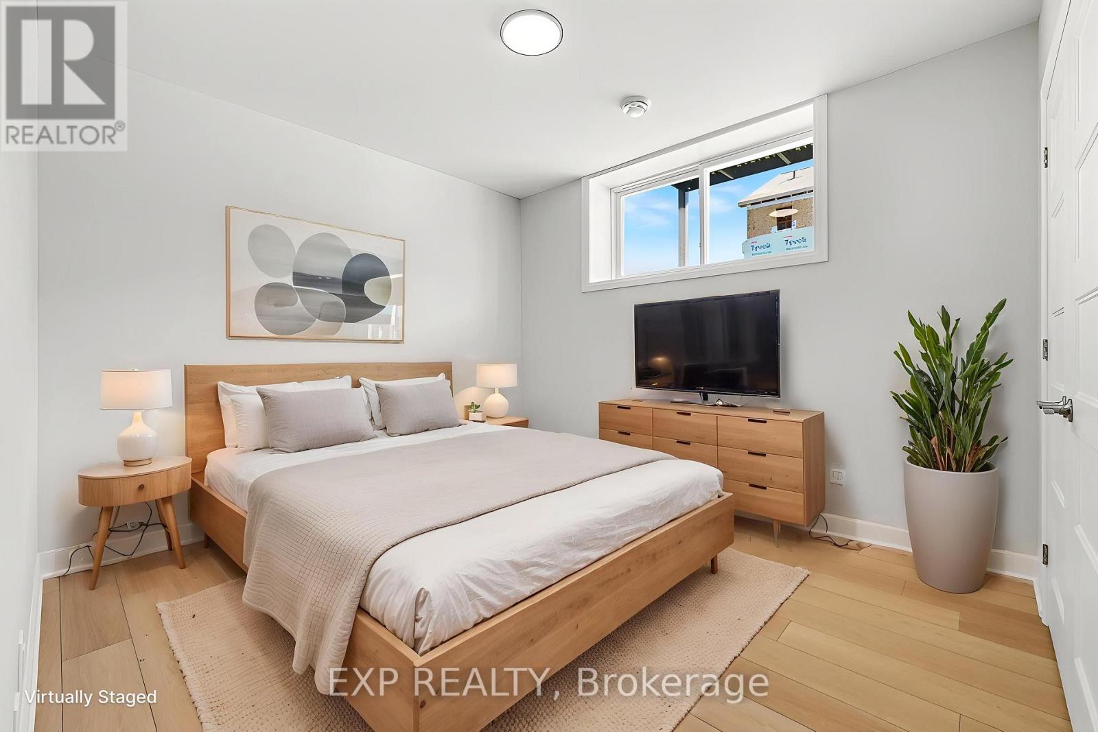 A bedroom with a bed, nightstand, and a plant.