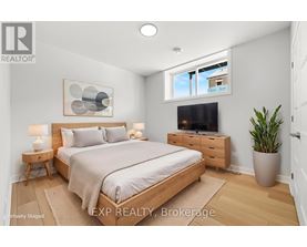 A bedroom with a bed, nightstand, and a plant.