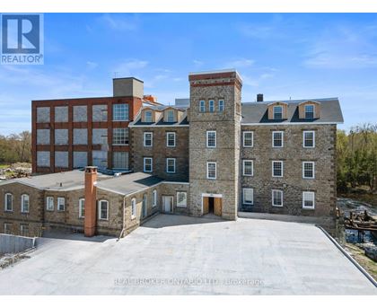 A large building with a flat roof and a chimney is surrounded by a parking lot.