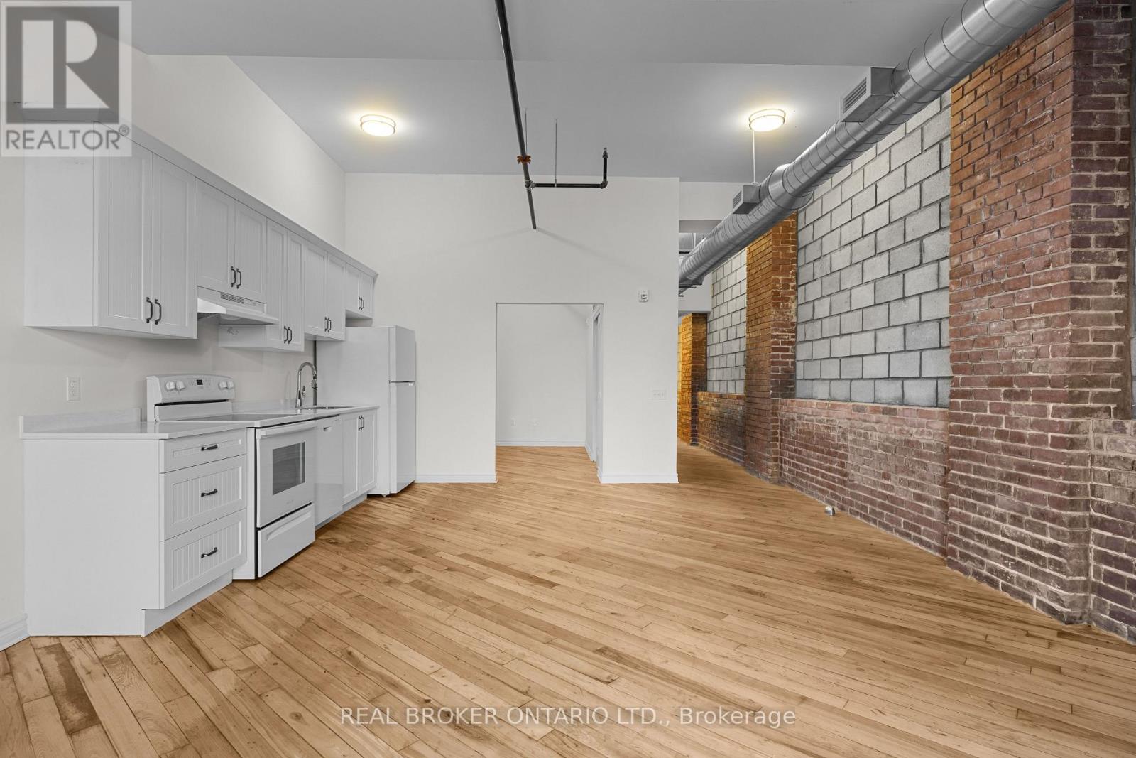 A kitchen with white cabinets and a wooden floor.