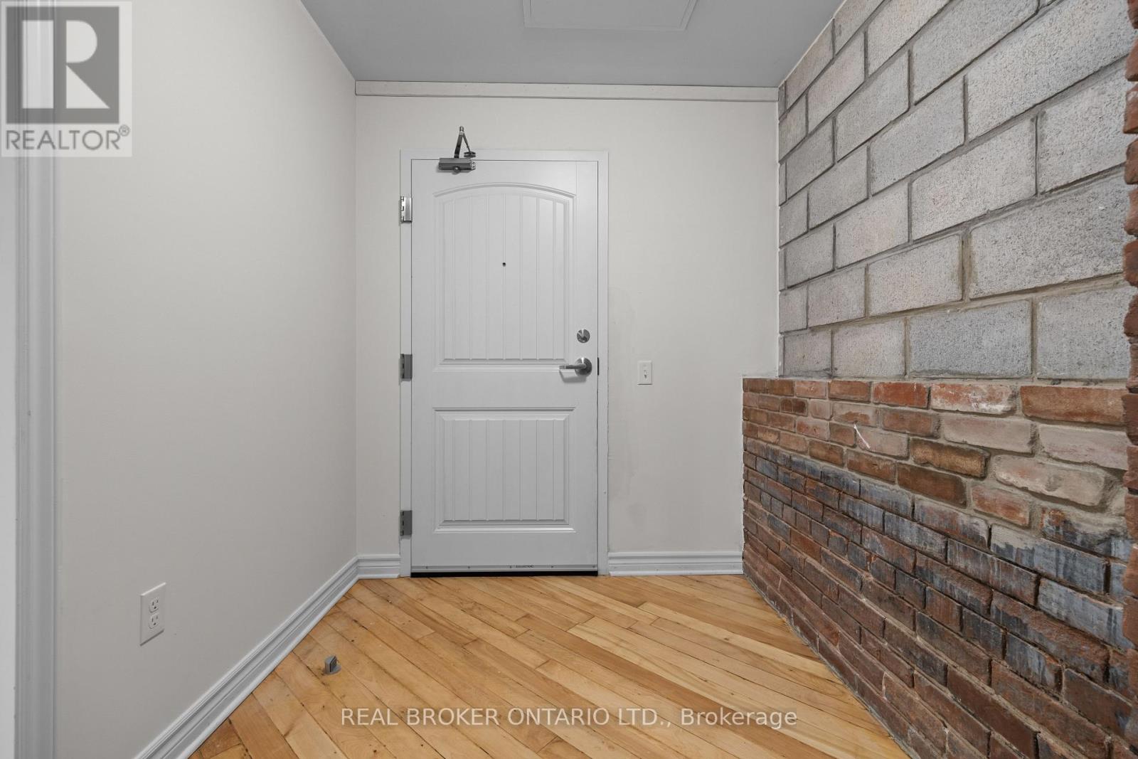 A white door in a room with a brick wall.