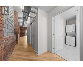 A hallway with a brick wall on the left and a white door on the right.