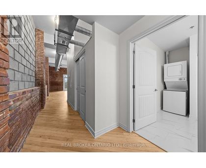 A hallway with a brick wall on the left and a white door on the right.