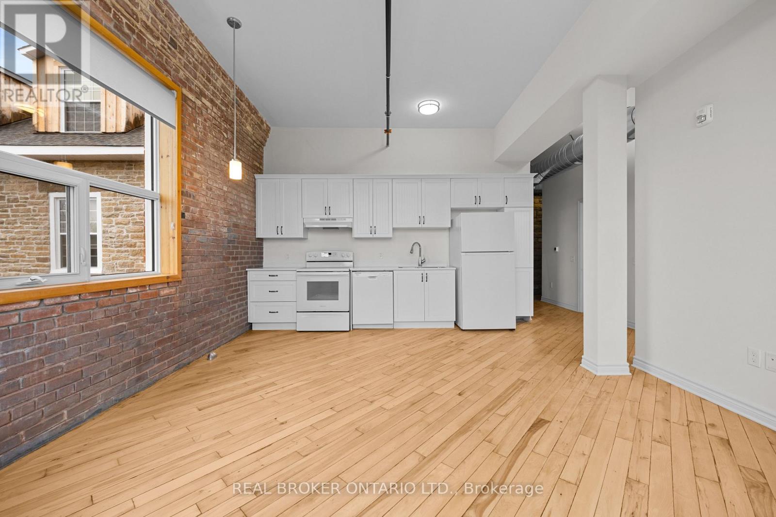A kitchen with white cabinets and a brick wall.