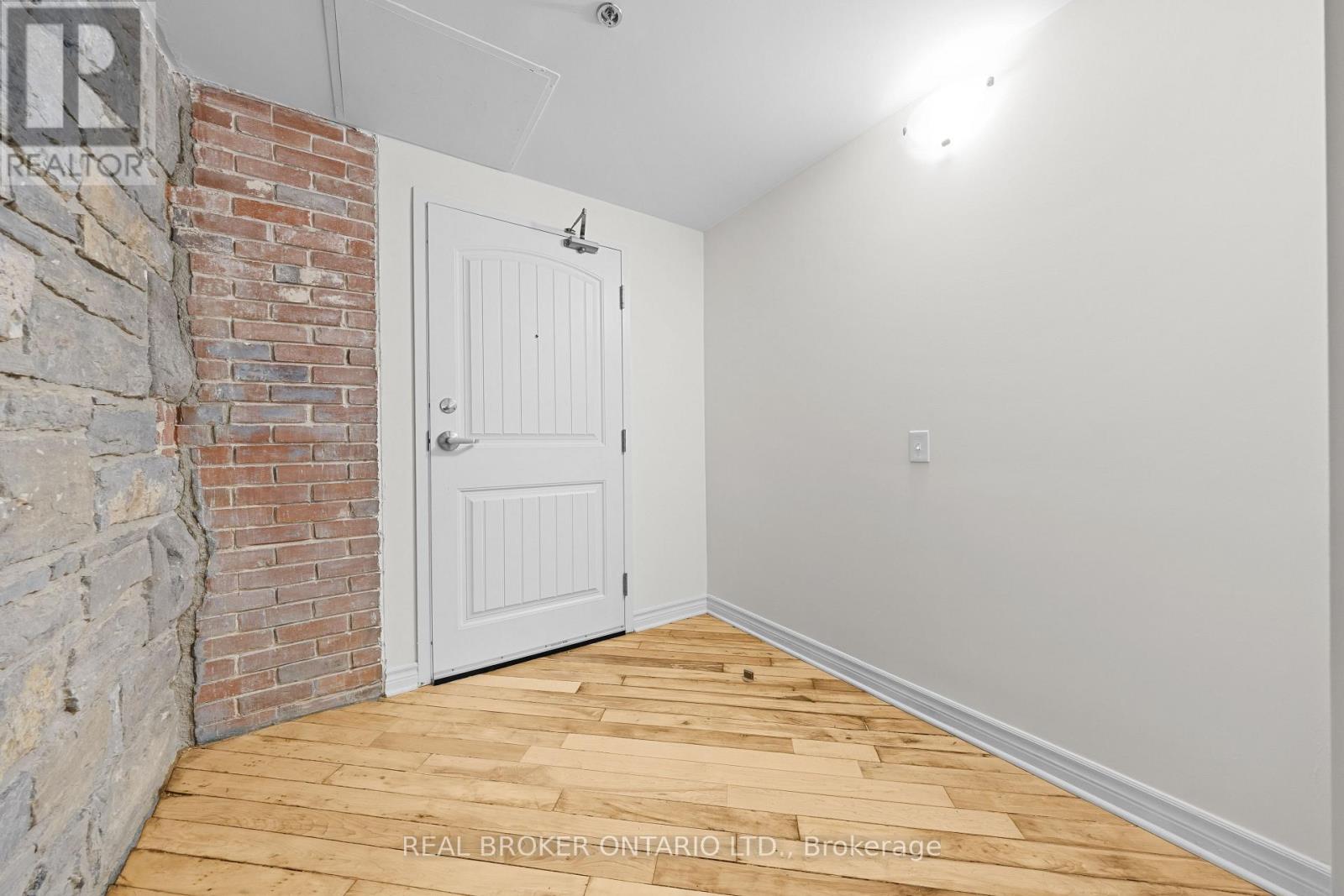 A room with a white door and a brick wall.