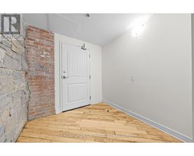 A room with a white door and a brick wall.