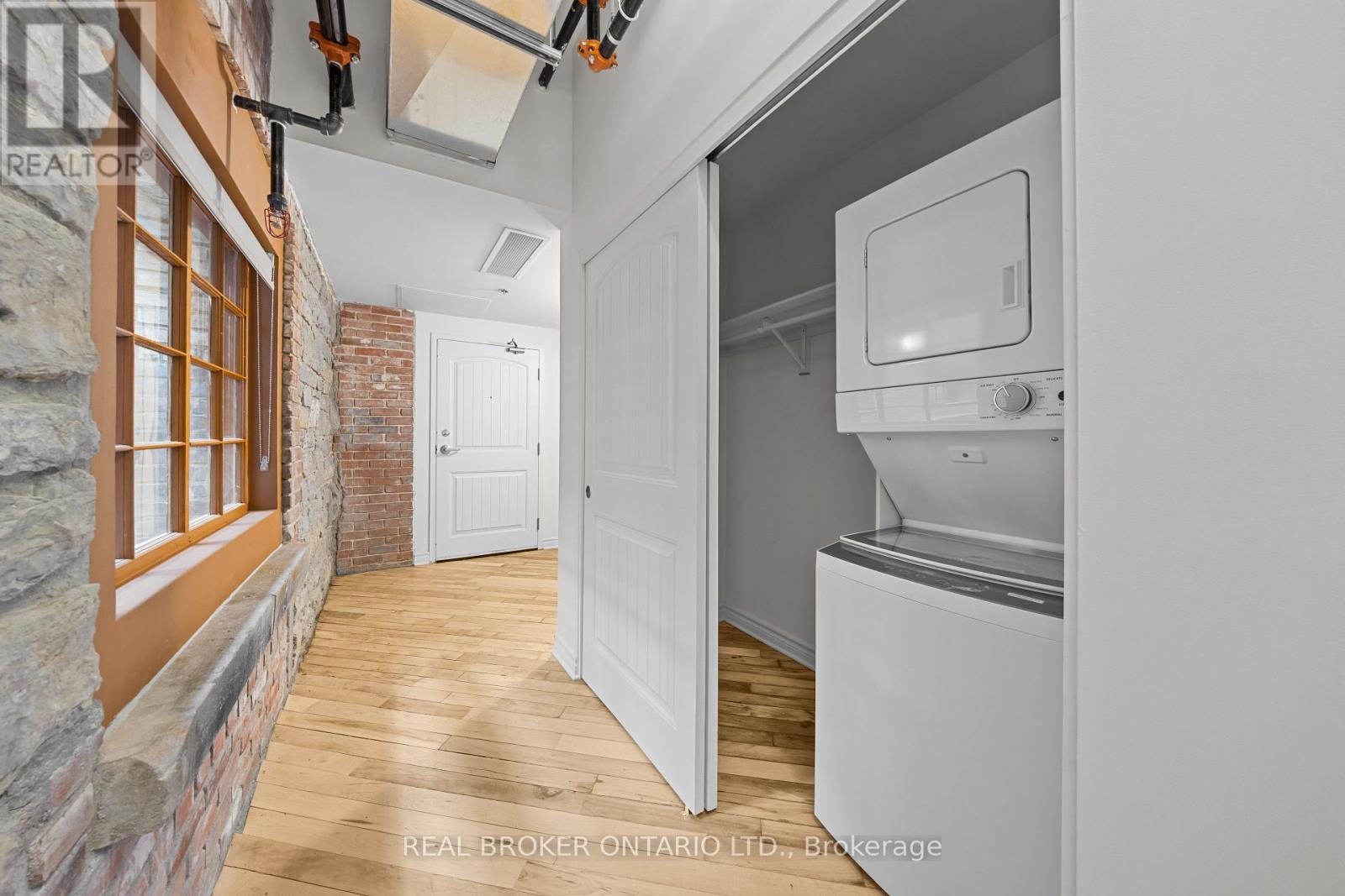 A kitchen with a white fridge and a brick wall.