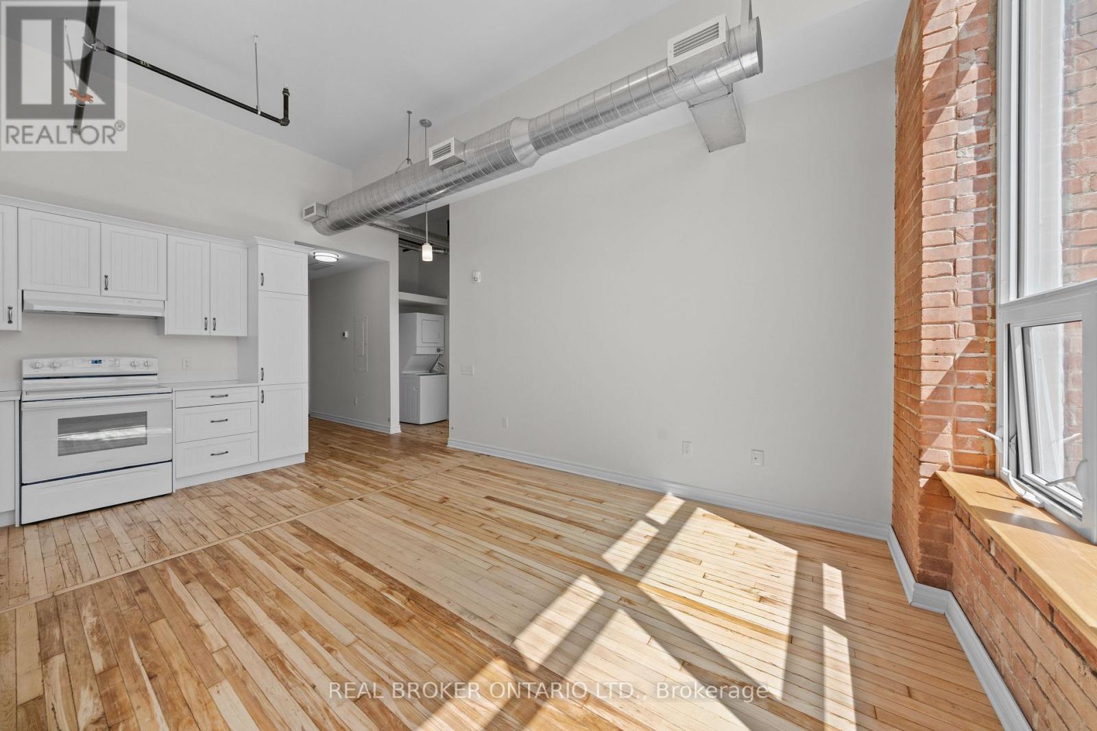 A spacious room with wooden flooring and a white wall.