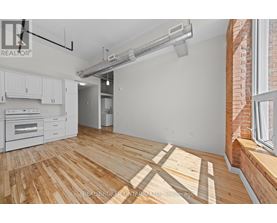 A spacious room with wooden flooring and a white wall.