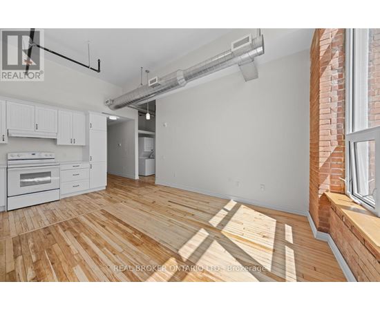 A spacious room with wooden flooring and a white wall.