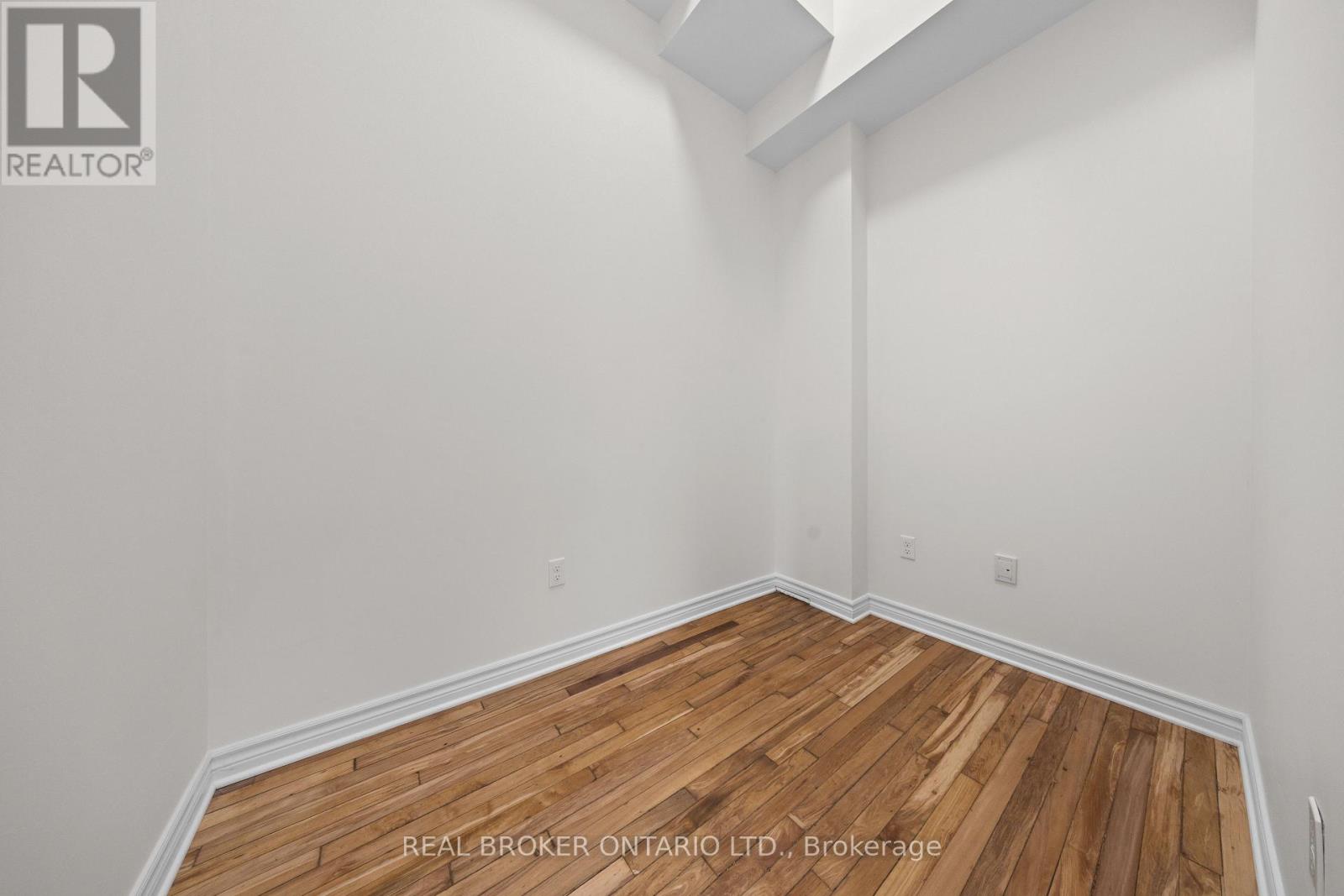 A realtor photo of a room with wood floors and white walls.
