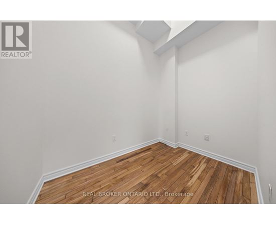 A realtor photo of a room with wood floors and white walls.
