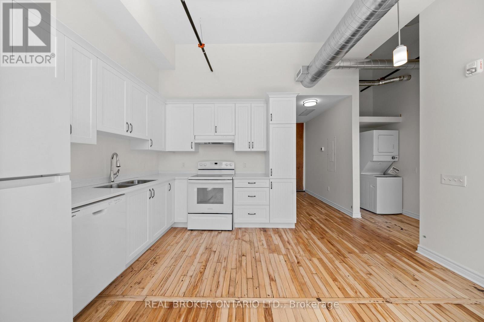 A kitchen with white cabinets and wooden floors.