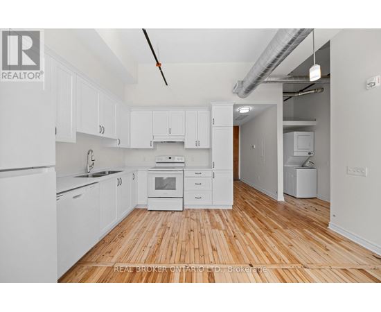 A kitchen with white cabinets and wooden floors.