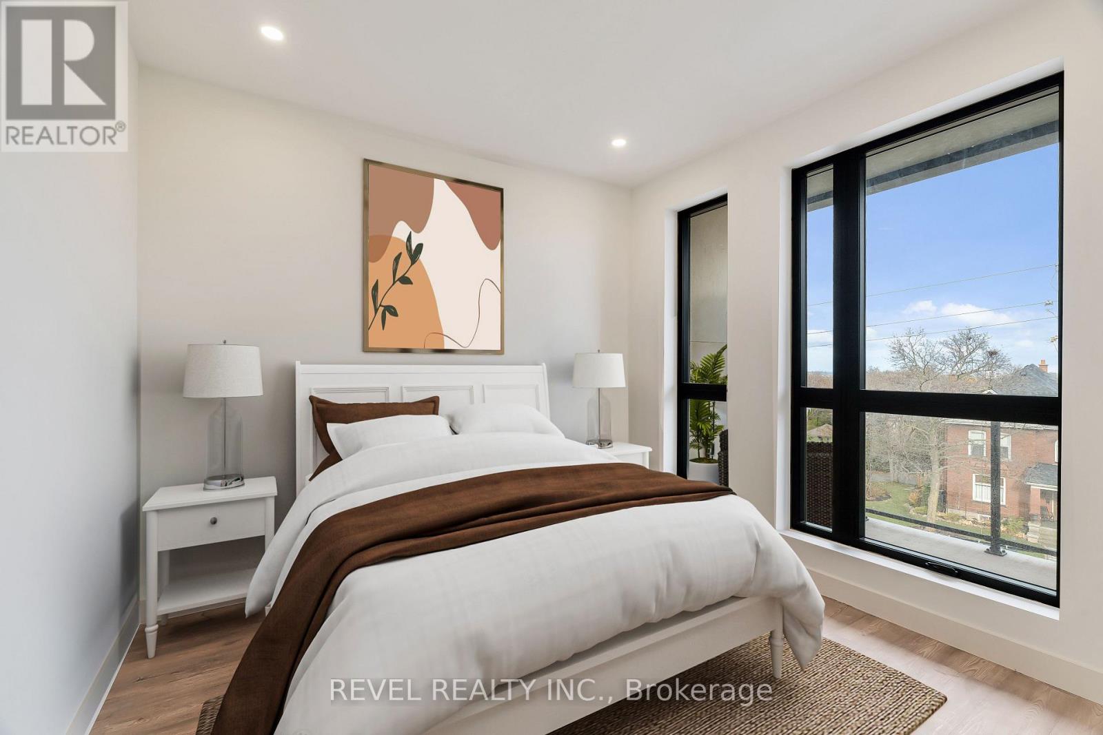 A bedroom with a large bed, a nightstand, and a window overlooking a brick building.