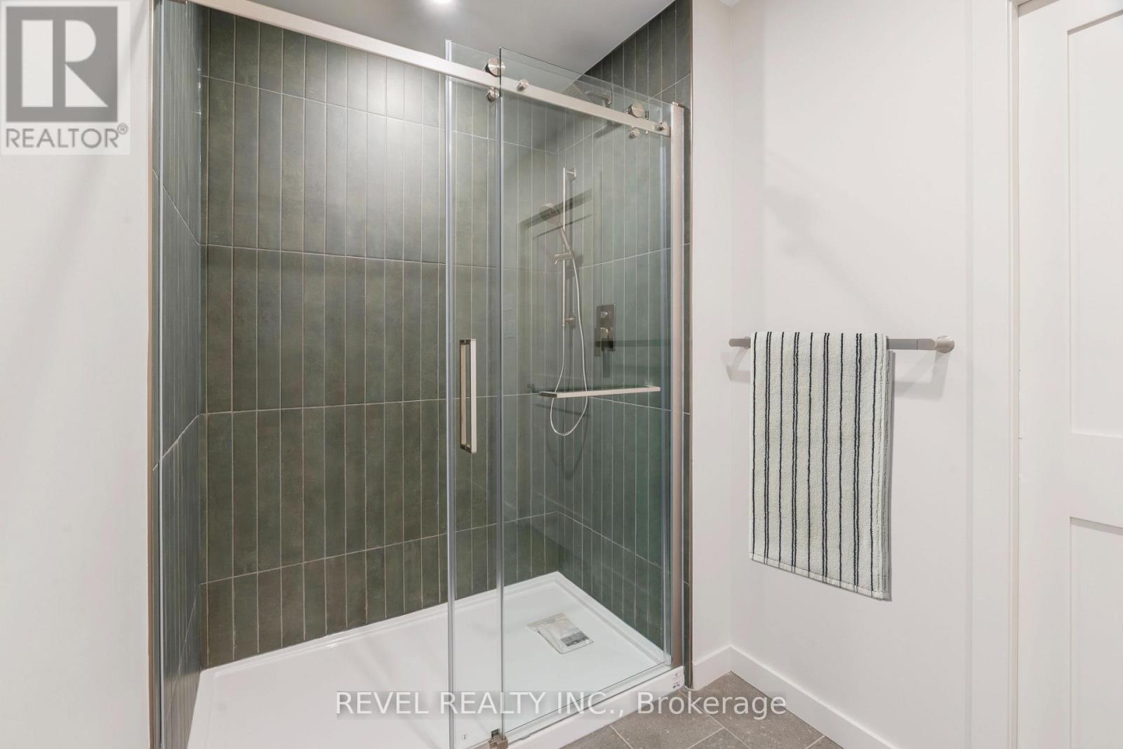 A bathroom with a glass shower door and a white wall.