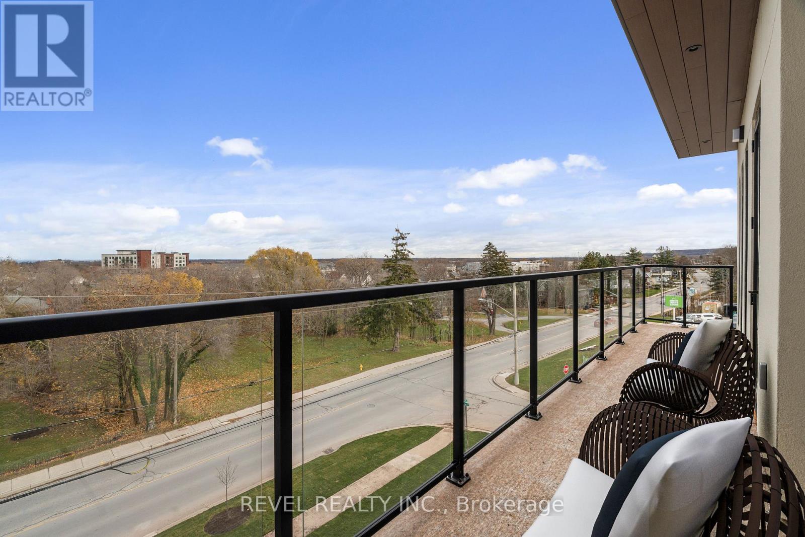 A balcony with chairs and a view of a road and trees.