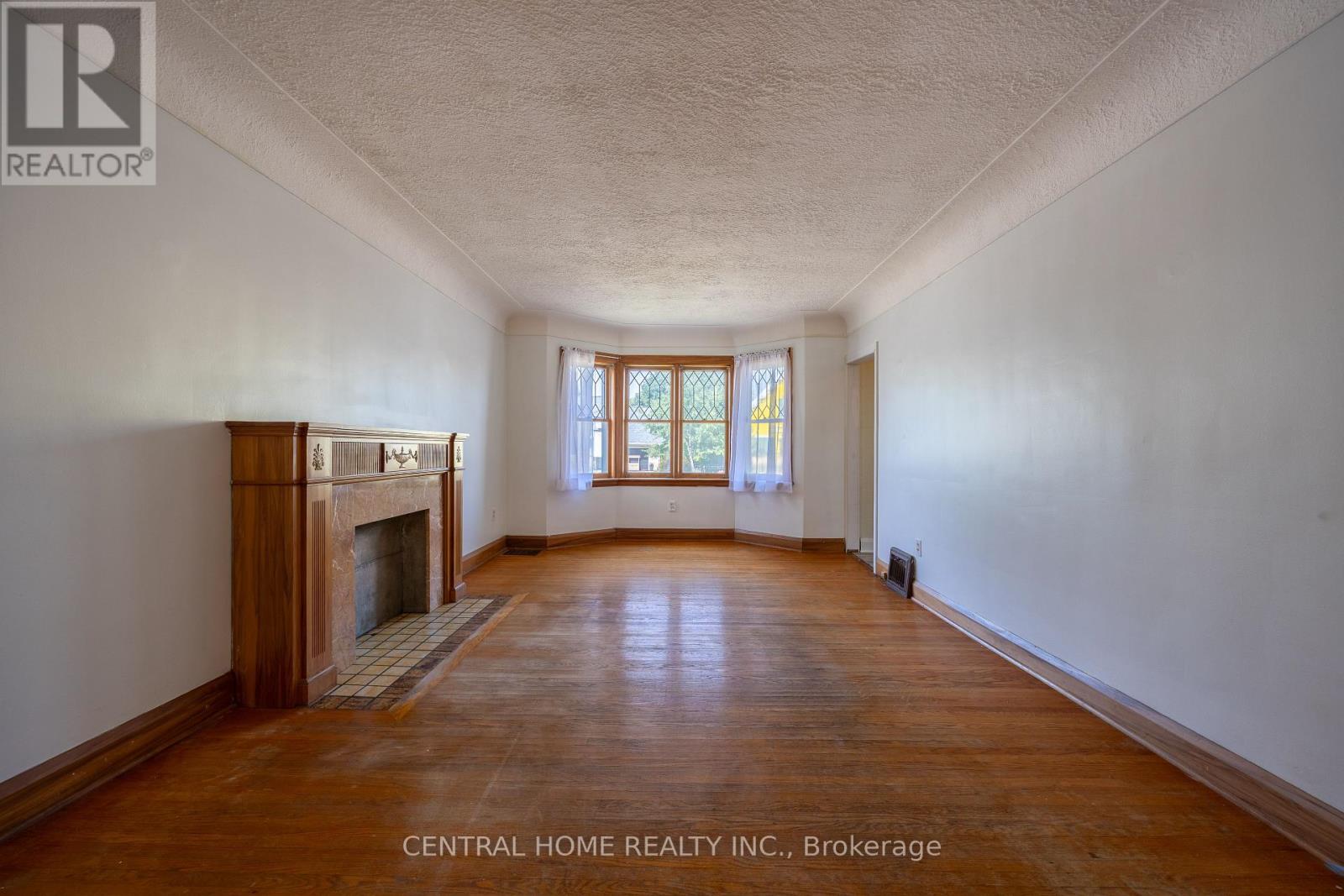A large, empty room with a fireplace and wooden floors.