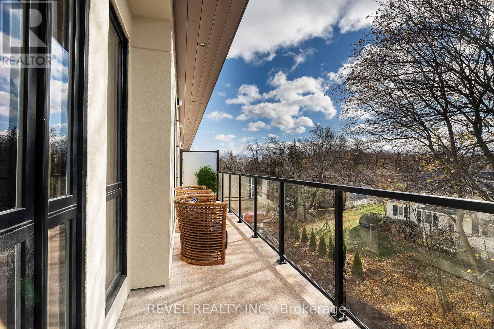 A balcony with a wicker chair and a view of trees.