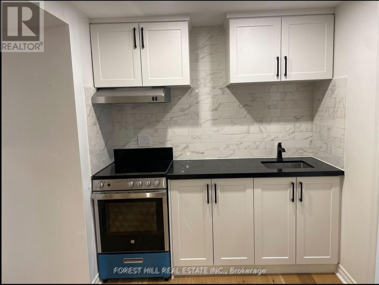 A kitchen with white cabinets and a black countertop.