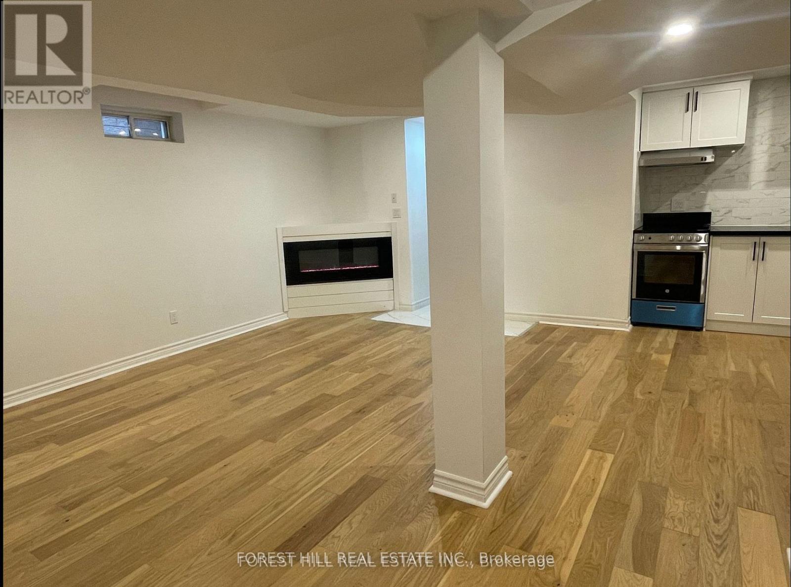 A room with wooden flooring and a column in the middle.