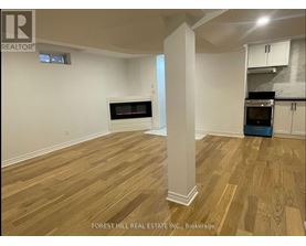A room with wooden flooring and a column in the middle.