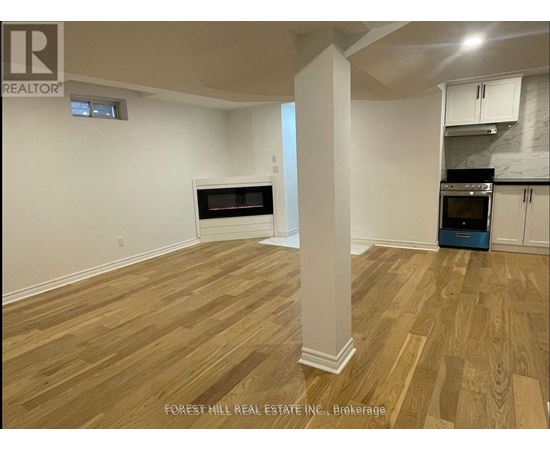 A room with wooden flooring and a column in the middle.